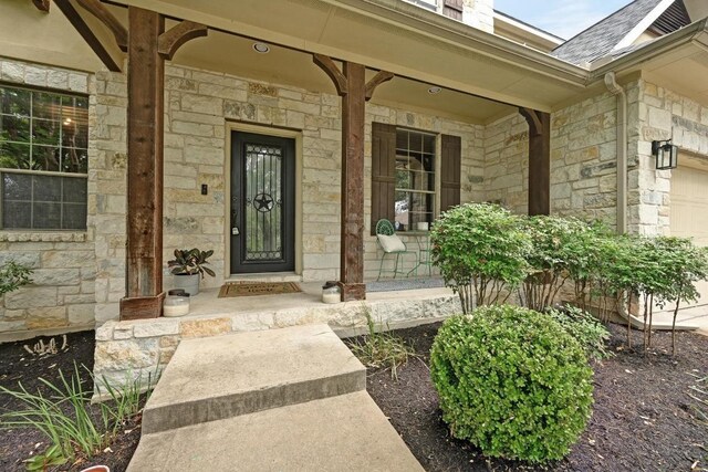 7716 Journeyville Dr, Austin, TX 78735 - doorway to property with stone siding, covered porch, roof with shingles, and an attached garage