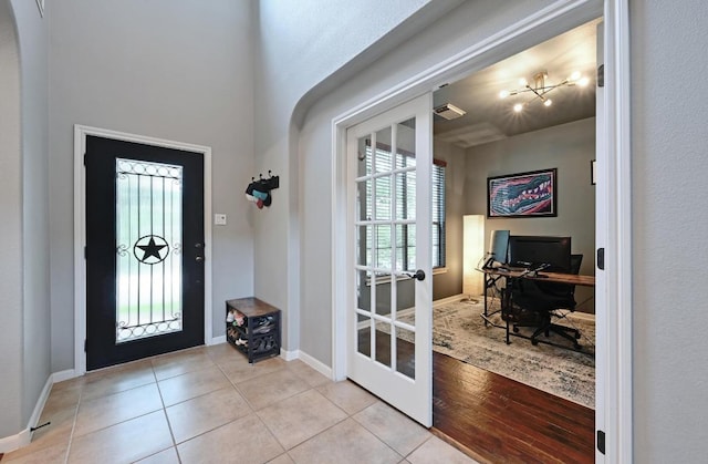 7716 Journeyville Dr, Austin, TX 78735 - foyer featuring light tile patterned floors, a chandelier, baseboards, and french doors