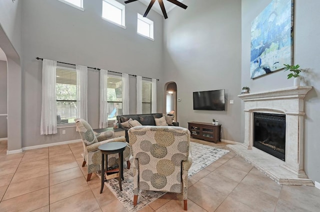 7716 Journeyville Dr, Austin, TX 78735 - living room featuring arched walkways, a high ceiling, ceiling fan, light tile patterned flooring, and a high end fireplace
