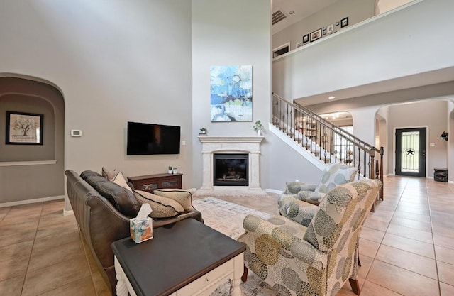 7716 Journeyville Dr, Austin, TX 78735 - living area with arched walkways, light tile patterned floors, a towering ceiling, and stairs