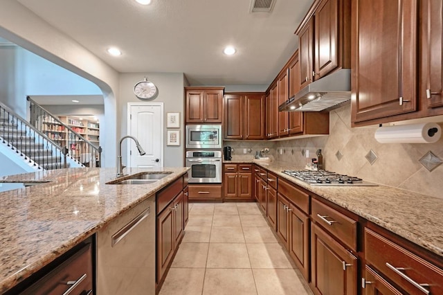 7716 Journeyville Dr, Austin, TX 78735 - kitchen with stainless steel appliances, under cabinet range hood, a sink, light stone countertops, and backsplash