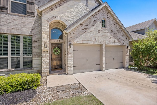 5609 Traviston Ct, Austin, TX 78738 - view of exterior entry featuring stone siding, an attached garage, concrete driveway, and brick siding