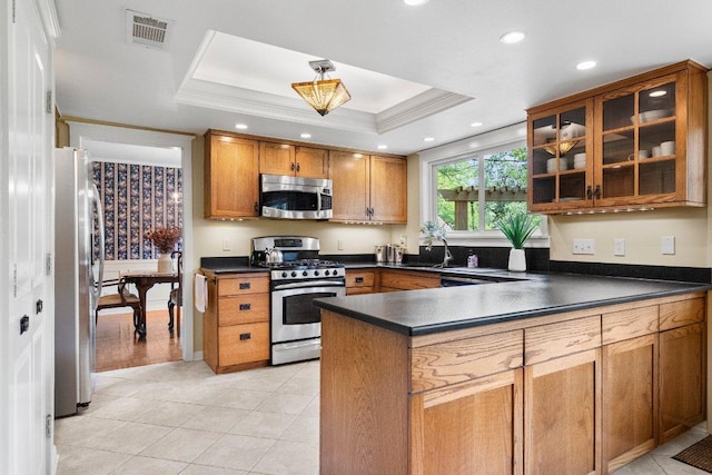 4101 Galacia Dr, Austin, TX 78759 - kitchen with stainless steel appliances, dark countertops, a tray ceiling, brown cabinets, and a peninsula