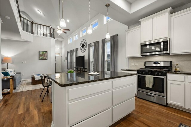 1404 Jenkins Bnd Unit 11, Austin, TX 78748 - kitchen featuring stainless steel appliances, a center island, dark wood-type flooring, a ceiling fan, and a towering ceiling