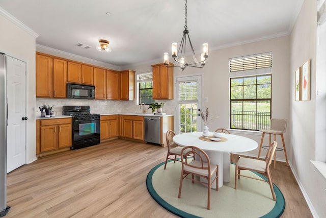 kitchen featuring light wood finished floors, light countertops, backsplash, black appliances, and a chandelier