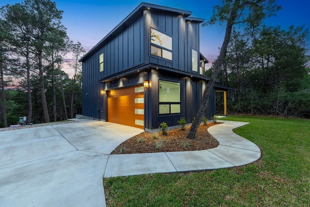 view of property exterior featuring board and batten siding, an attached garage, a yard, and concrete driveway
