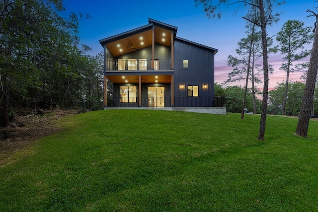 back of property at dusk featuring a yard and a balcony