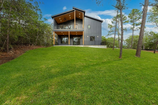 rear view of property with a balcony and a yard