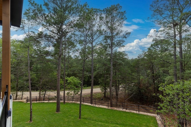 view of yard with a forest view and fence