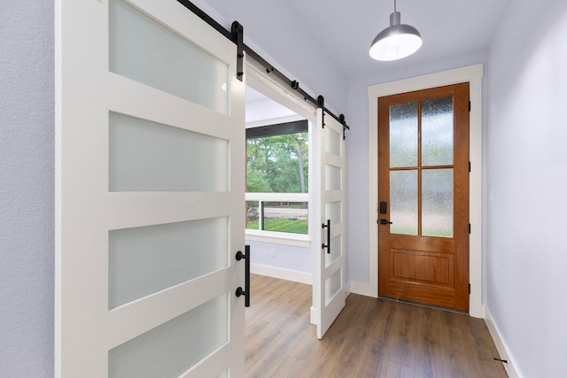 doorway to outside featuring a barn door, baseboards, and wood finished floors