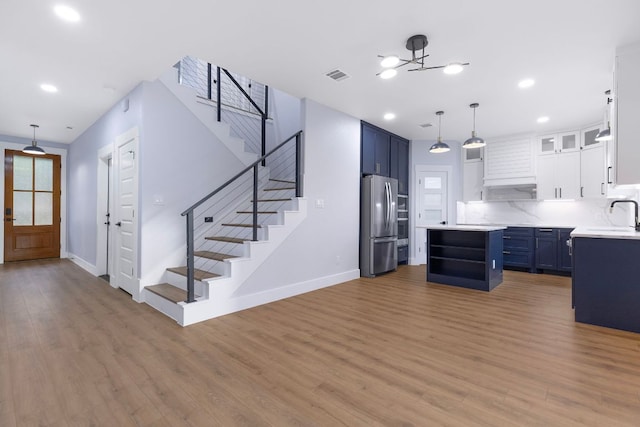 kitchen with a sink, light wood-style floors, light countertops, blue cabinetry, and freestanding refrigerator