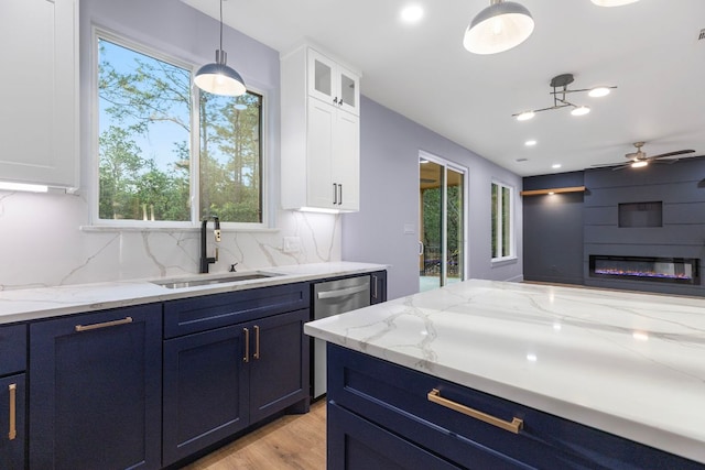 kitchen featuring stainless steel dishwasher, white cabinetry, and a sink