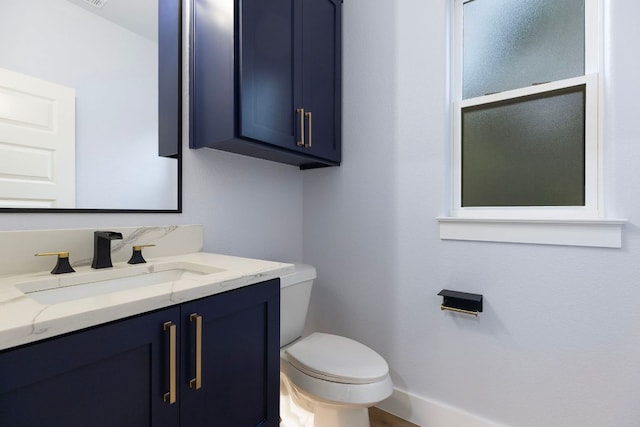 bathroom with baseboards, vanity, and toilet