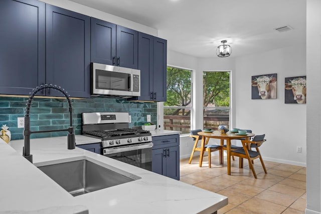 104 Summerwood Cv, San Marcos, TX 78666 - kitchen featuring appliances with stainless steel finishes, tasteful backsplash, light stone counters, blue cabinetry, and light tile patterned flooring