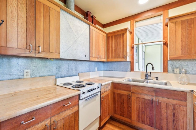 kitchen with decorative backsplash, light countertops, a sink, and white range with electric cooktop
