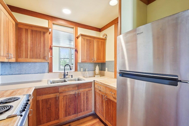 kitchen featuring a sink, light wood-style floors, range, light countertops, and freestanding refrigerator