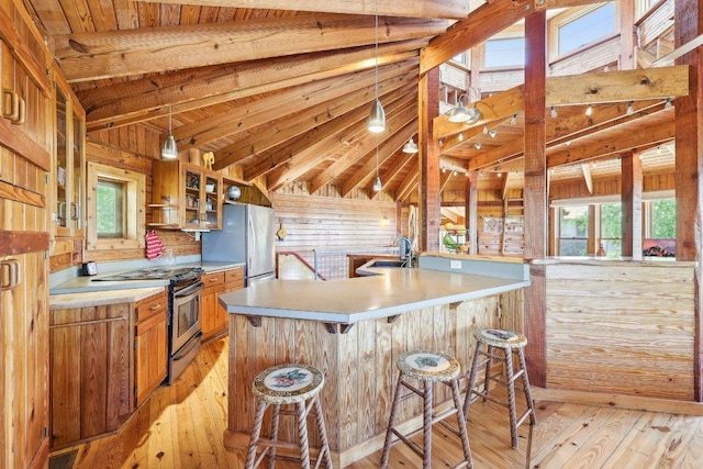 kitchen with lofted ceiling with beams, stainless steel appliances, a sink, brown cabinets, and light countertops