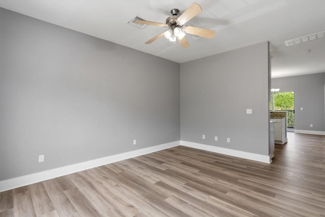 spare room with baseboards, a ceiling fan, wood finished floors, and visible vents