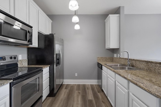 kitchen featuring white cabinets, stainless steel appliances, a sink, baseboards, and dark wood-type flooring