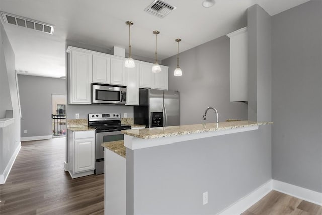 kitchen featuring a peninsula, visible vents, light stone counters, and appliances with stainless steel finishes