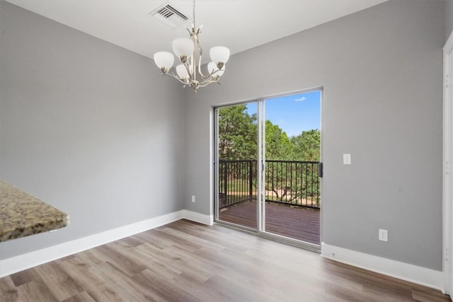 unfurnished dining area featuring an inviting chandelier, wood finished floors, visible vents, and baseboards
