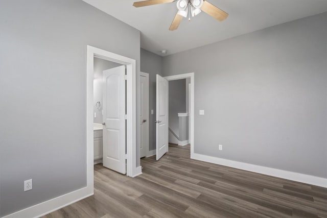 unfurnished bedroom with baseboards, a ceiling fan, wood finished floors, and ensuite bathroom