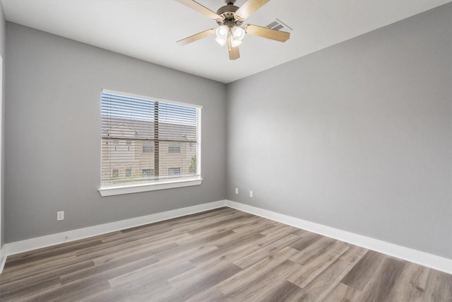 empty room featuring baseboards, a ceiling fan, wood finished floors, and visible vents