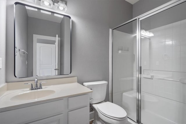bathroom featuring toilet, vanity, and a stall shower