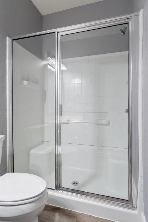 full bath with a shower stall, toilet, and wood finished floors