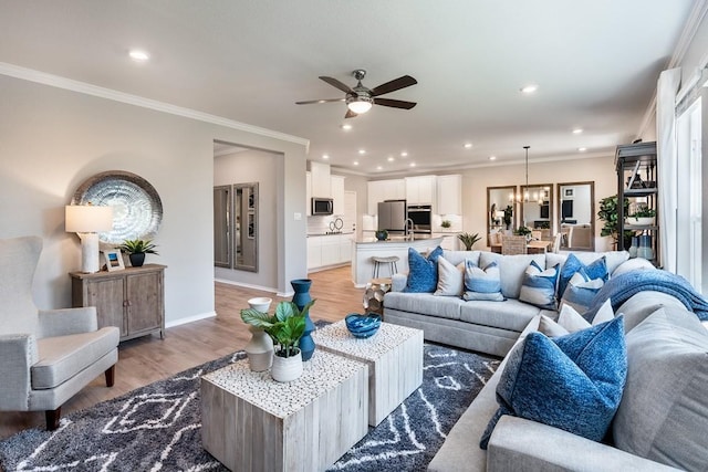 1100 Cole Estates Dr, Georgetown, TX 78628 - living room featuring recessed lighting, light wood-style floors, baseboards, ornamental molding, and ceiling fan with notable chandelier