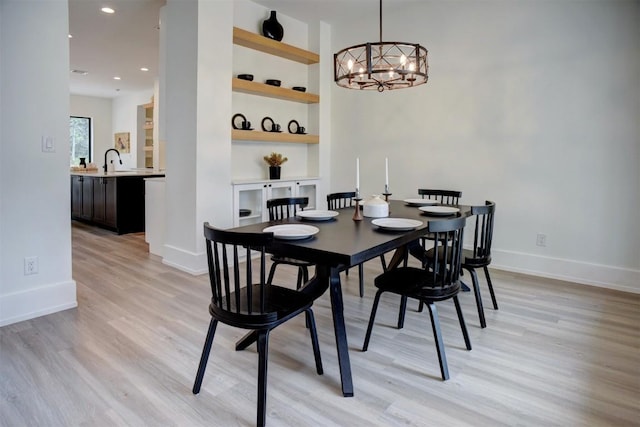 dining space featuring an inviting chandelier, built in features, light wood finished floors, baseboards, and recessed lighting
