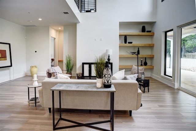 living room with baseboards, visible vents, and light wood-type flooring