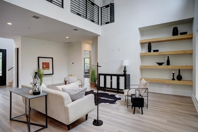 living area featuring wood finished floors, a high ceiling, baseboards, and visible vents