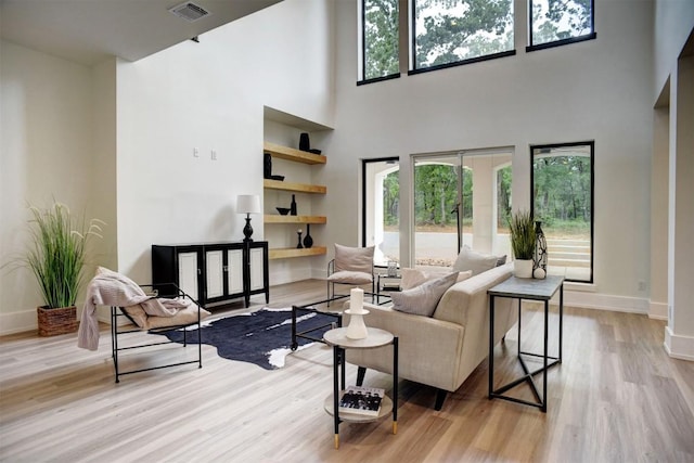 living area with baseboards, wood finished floors, visible vents, and plenty of natural light