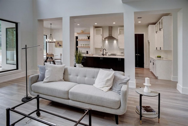 living area with recessed lighting, an inviting chandelier, light wood finished floors, and baseboards