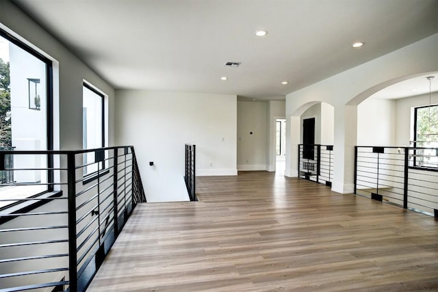 spare room featuring arched walkways, baseboards, visible vents, recessed lighting, and wood finished floors