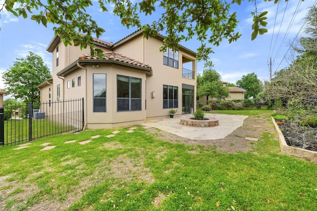 rear view of property featuring a tile roof, fence, a patio area, a lawn, and stucco siding
