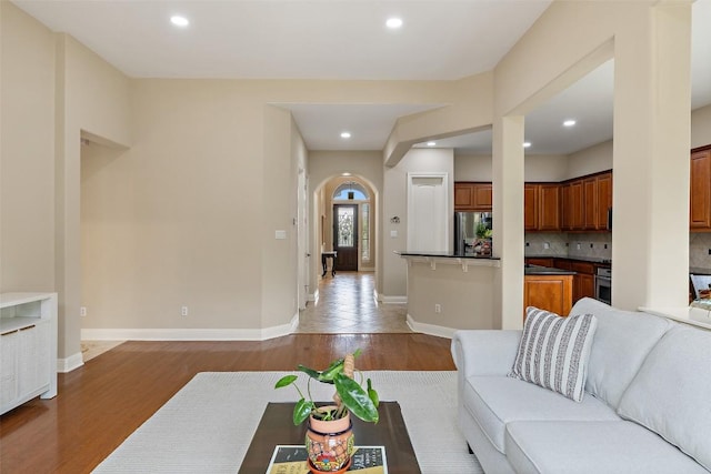 living room featuring arched walkways, wood finished floors, and recessed lighting