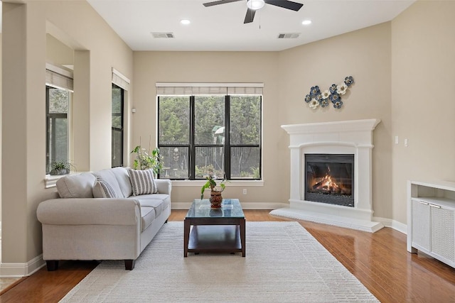 living room with ceiling fan, a healthy amount of sunlight, wood finished floors, and visible vents