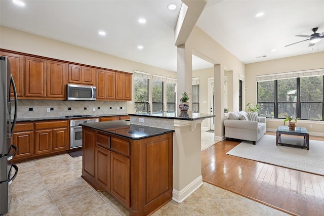 kitchen with brown cabinets, a wealth of natural light, appliances with stainless steel finishes, and open floor plan