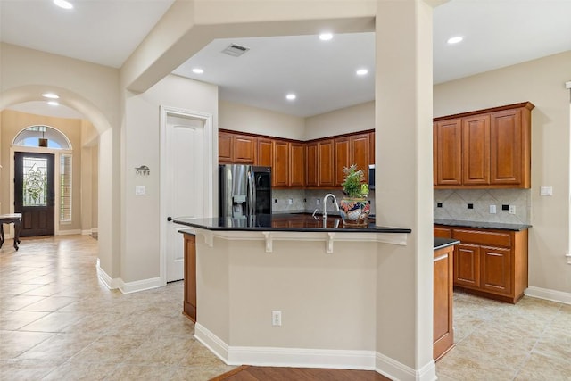 2328 Gilia Dr, Austin, TX 78733 - kitchen featuring stainless steel refrigerator with ice dispenser, tasteful backsplash, recessed lighting, light tile patterned floors, and brown cabinets