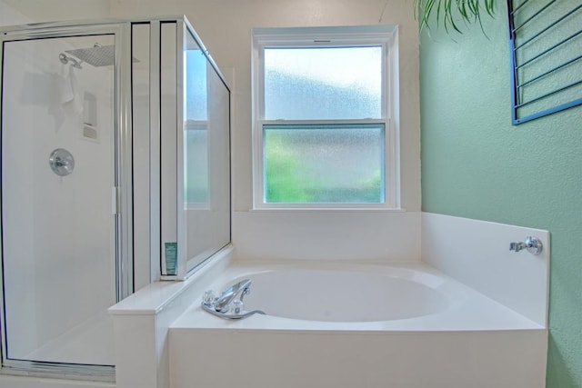 full bath featuring a shower stall, a garden tub, and a textured wall