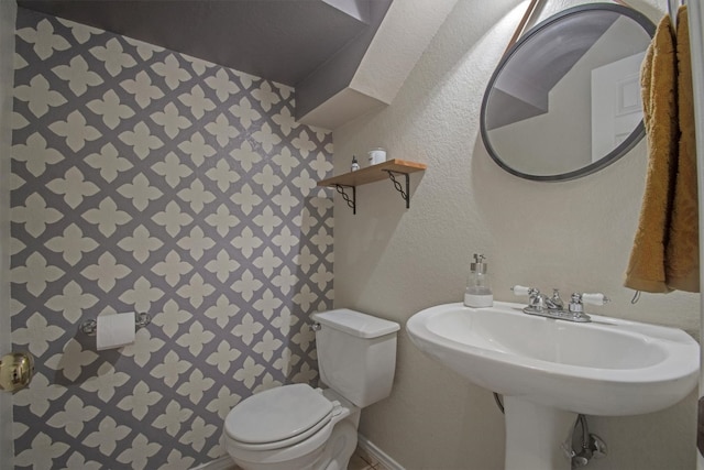 half bathroom with a textured wall and toilet