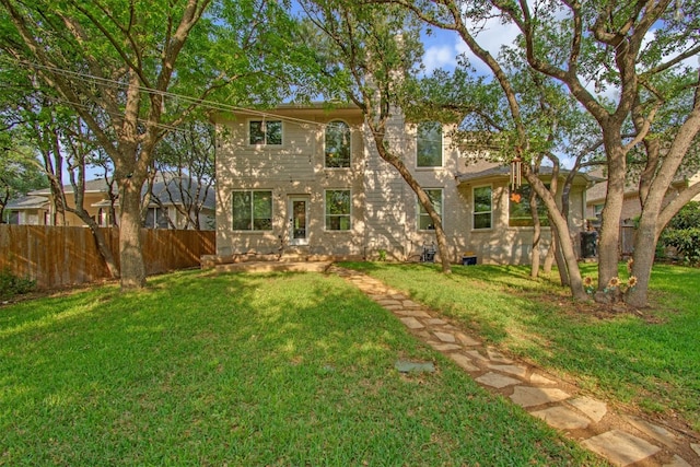 rear view of property with a lawn and fence