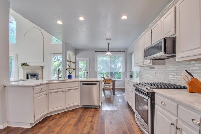 kitchen featuring a sink, white cabinets, light countertops, wood-type flooring, and appliances with stainless steel finishes