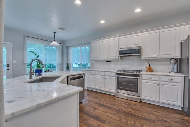 kitchen with a sink, appliances with stainless steel finishes, backsplash, white cabinetry, and visible vents