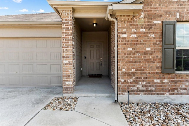 property entrance with brick siding, a garage, and concrete driveway