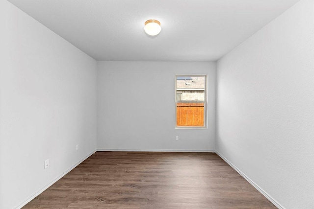 spare room featuring baseboards and wood finished floors