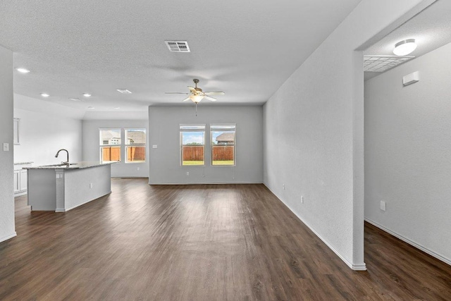 unfurnished living room with a ceiling fan, baseboards, a sink, and dark wood-type flooring