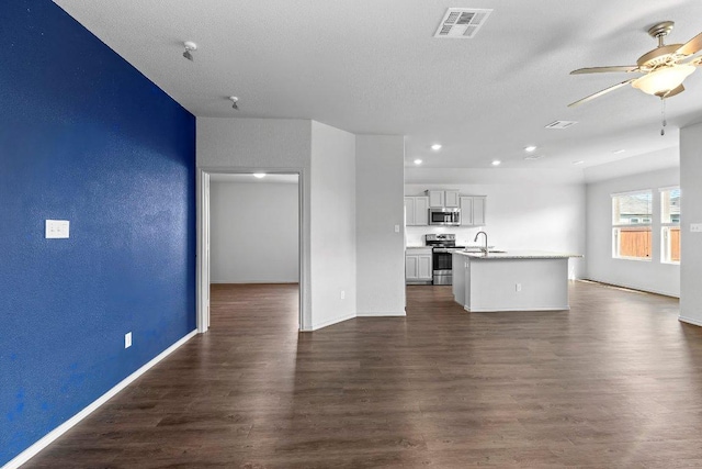 unfurnished living room with a ceiling fan, baseboards, dark wood-type flooring, visible vents, and recessed lighting
